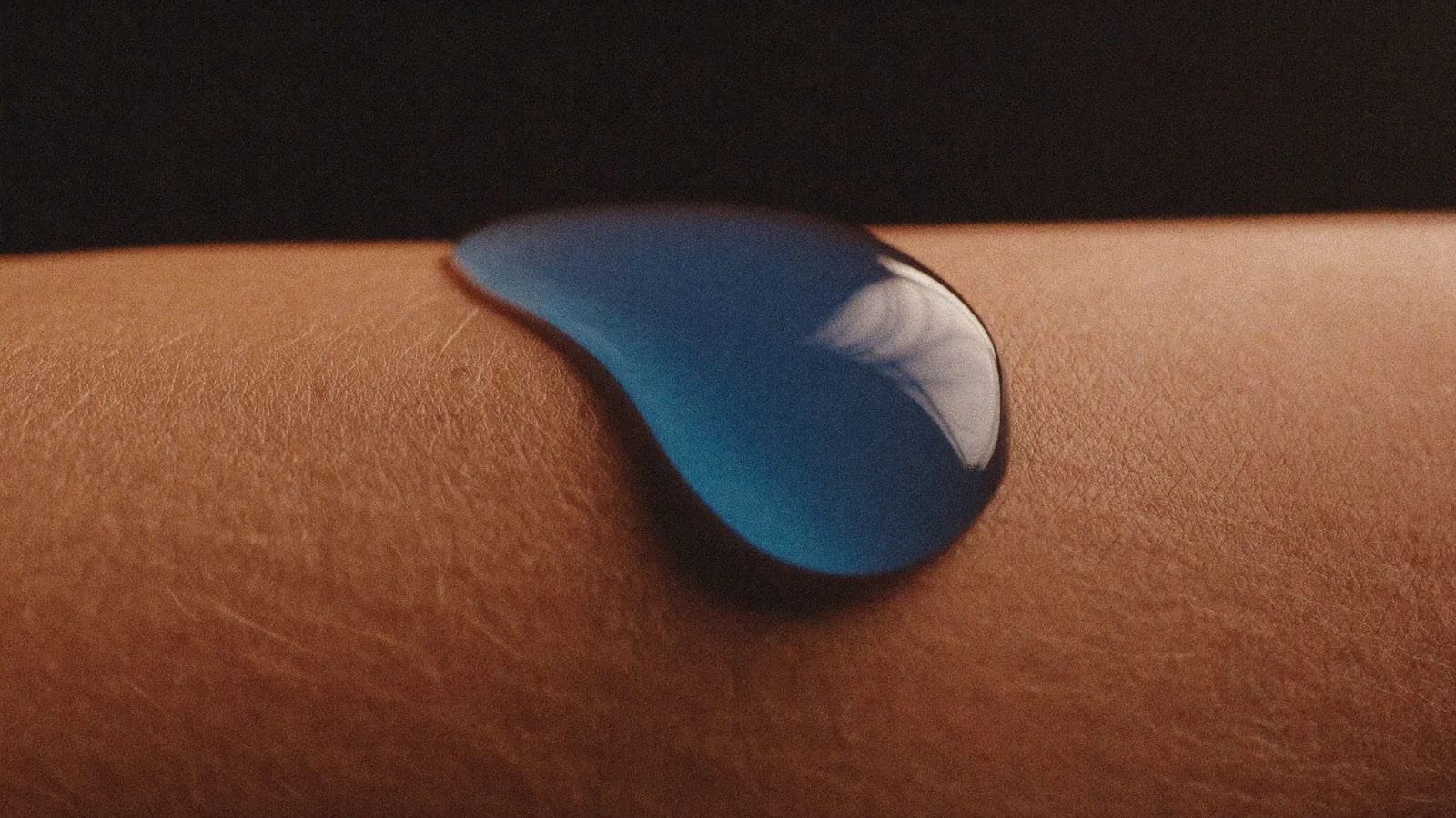 A luminous drop of serum resting on skin